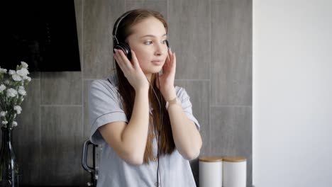 lovely teenage girl is listening music in headphones indoor