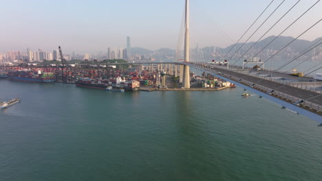 traffic drives over high suspension bridge while container ships are moored at the terminal