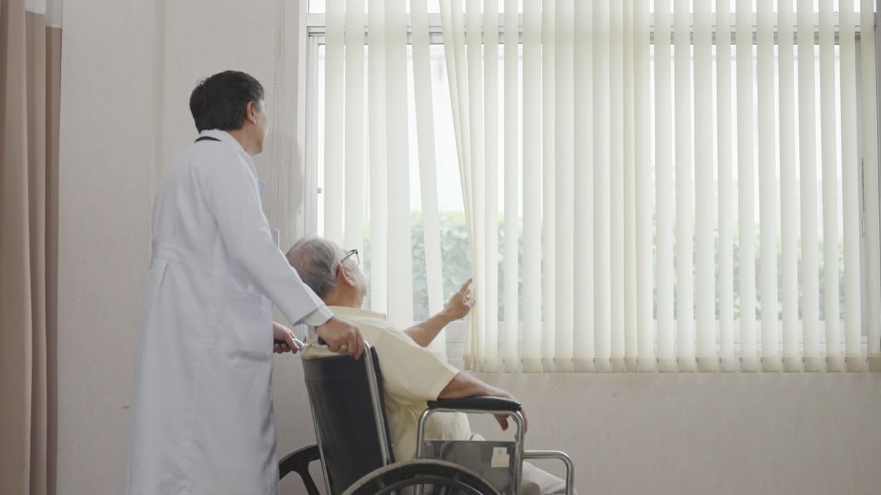 médico y un anciano asiático se sienta en una silla de ruedas y mira por la ventana. cuidado de la salud y seguros, concepto de jubilación