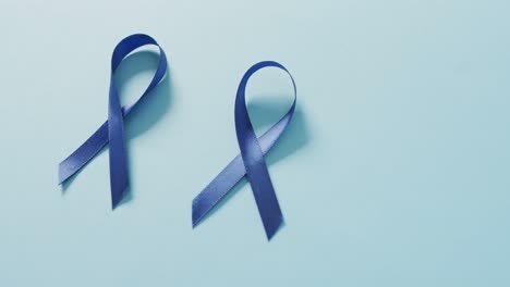 video of two dark blue colon cancer ribbons on pale blue background