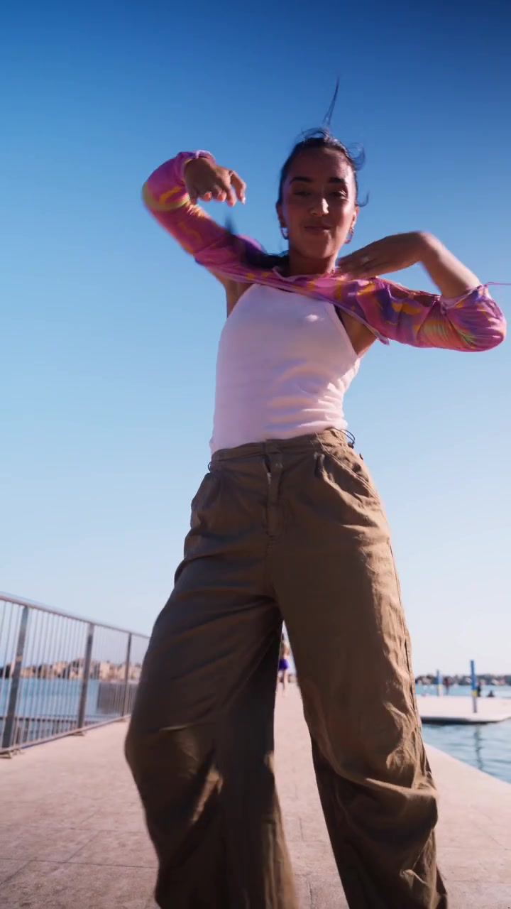 Young Woman Dancing Outdoors on a Sunny Pier