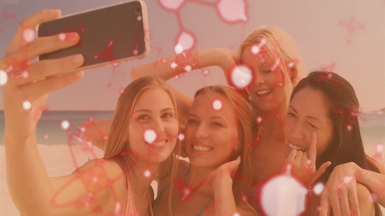 Women taking selfie at beach with red molecular animation overlay
