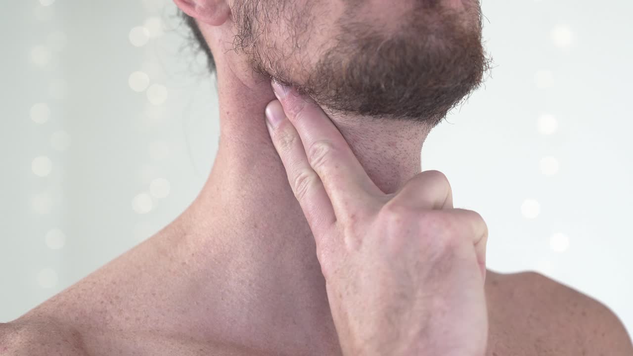 un primer plano de un hombre en topless sintiendo su pulso carotídeo con los dedos.