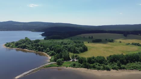 Filmische-Ansicht-Der-Drohne,-Wie-Sie-Von-Oben-über-Die-Landschaft-Und-Auch-über-Den-Großen-Blauen-See-Rotiert