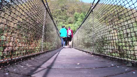 adventurous couple, man and woman, crossing a suspension bridge in fragas do eume, galicia, during a sunny day