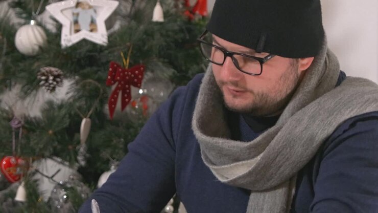 Uomo infreddolito, turbato e ansioso che ordina una pila di bollette finanziarie a Natale