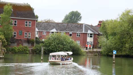 a boat cruises past buildings and greenery