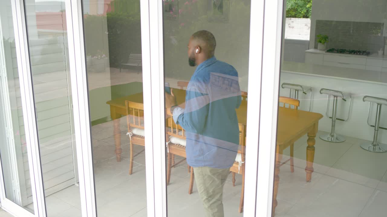 Vídeo vertical: Homem com camisa jeans e calças cáqui caminhando, reagindo ao aviso do telefone, gesticulando em casa.