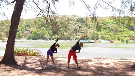 couple stretching outdoors by a lake
