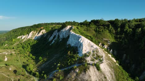 aerial view of a geological formation with white cliffs and green forests