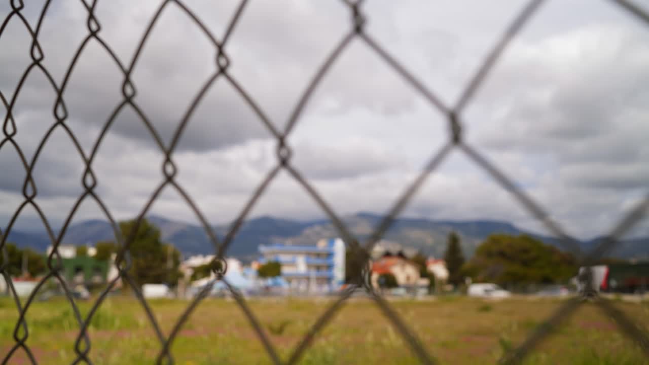 Landscape at New Erithrea , North Attica, Greece focus pull revealed behind a wire fence , beautiful cloud formations over mountains 4K