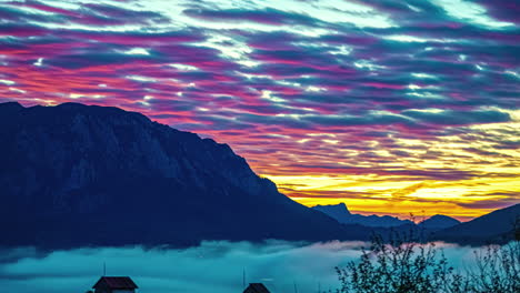 coucher de soleil de feu de lumière rouge vibrante reflétant sur les nuages du ciel orange au-dessus des montagnes pittoresques et de la couche de brouillard épais