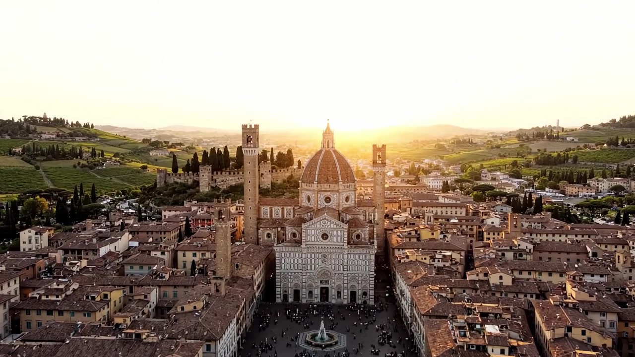 Vista aerea di una maestosa cupola circondata da architettura storica e dolci colline durante un tramonto dorato.