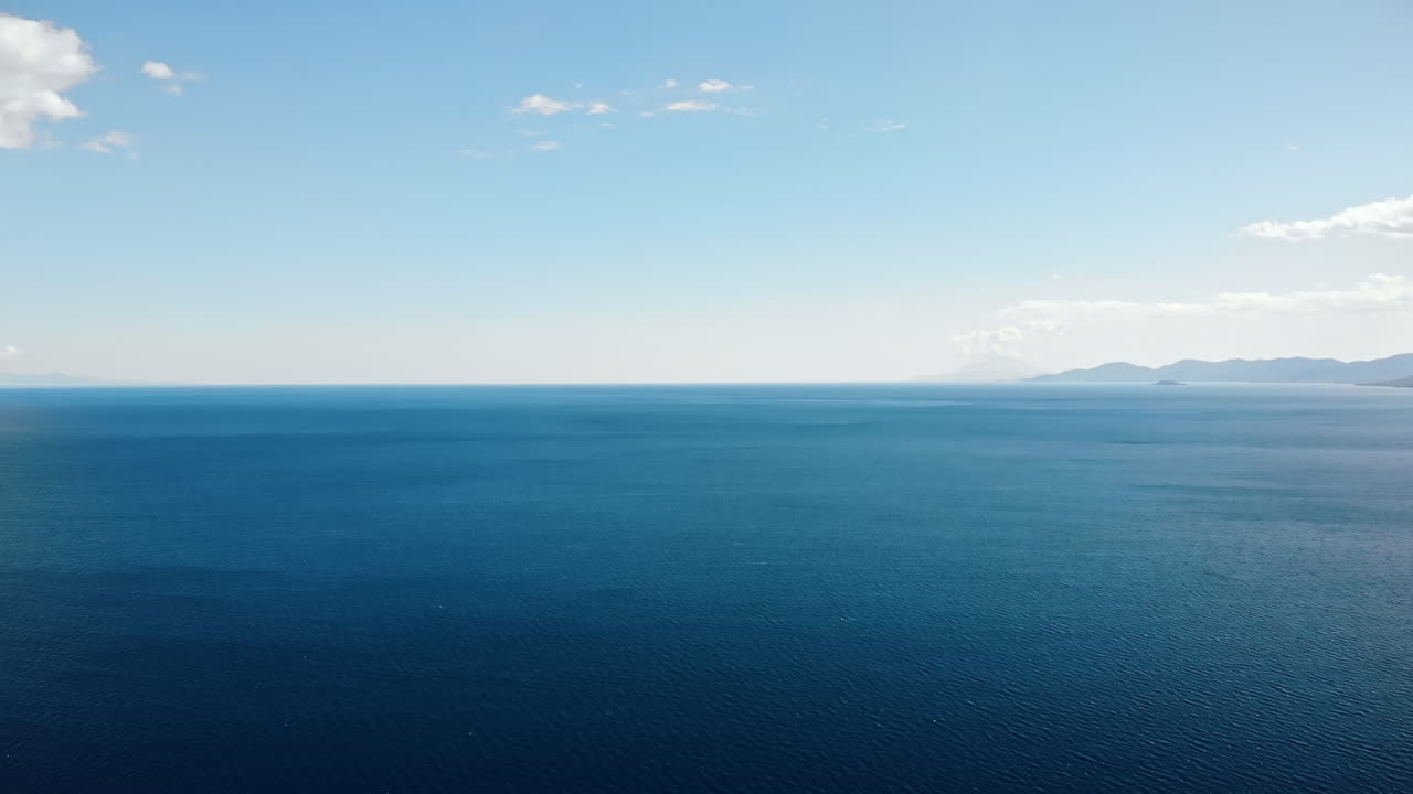 Panorama of the Asprovalta located on the Aegean sea coast with buildings and greenery, green hills. Long beach along the town. Sunny day, view from the drone. Greece