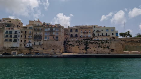 valetta, city of malta coastal apartment buildings from moving boat