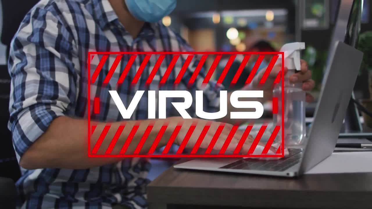 texto del virus contra el hombre que lleva la máscara limpiando la computadora portátil con desinfectante en la oficina
