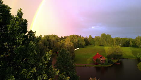 cabaña junto al lago, colores pastel y arco iris en el cielo
