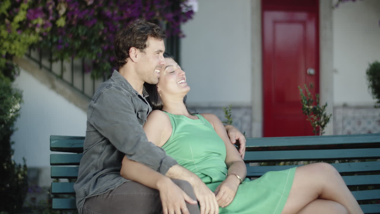 행복한 커플이 벤치에 앉아 포옹하고 키스하고 있습니다.