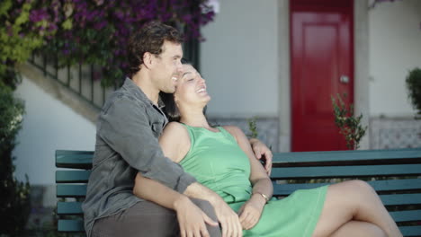 una pareja feliz sentada en un banco, abrazándose y besándose.
