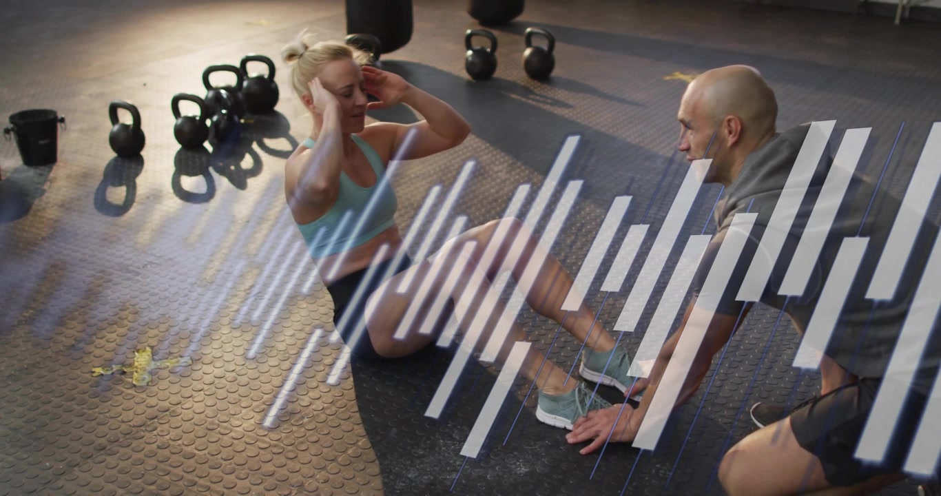 Male trainer bracing client's feet, female client doing crunches on black mat for core strength