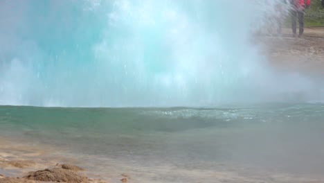 strokkur geyser erupts in a slow motion bubble in front of tourists in iceland