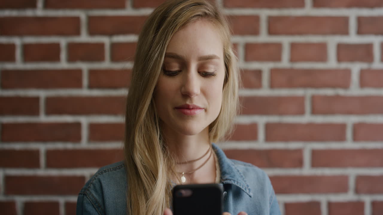 ritratto carina giovane studentessa bionda che usa lo smartphone leggendo messaggi godendosi la navigazione e i messaggi sul cellulare