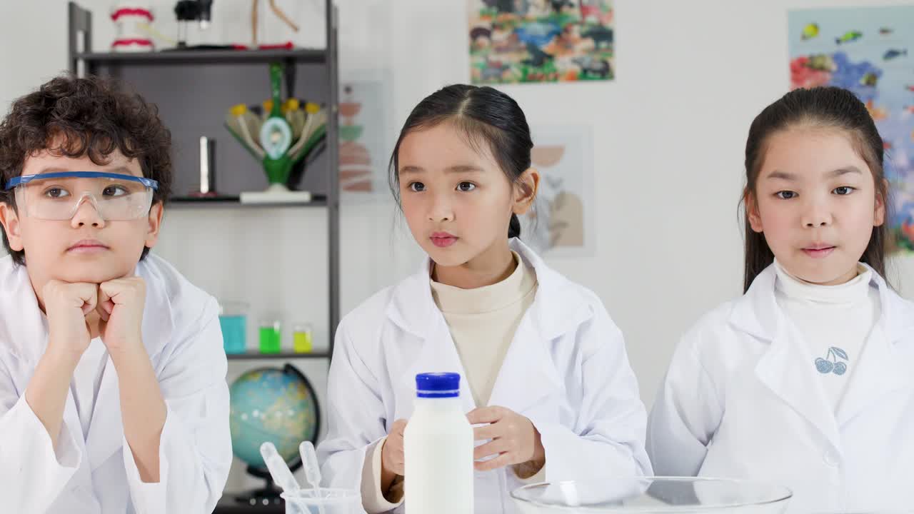 学校で、タイの子供たちが白衣とゴーグルを着用し、化学実験を行っている。