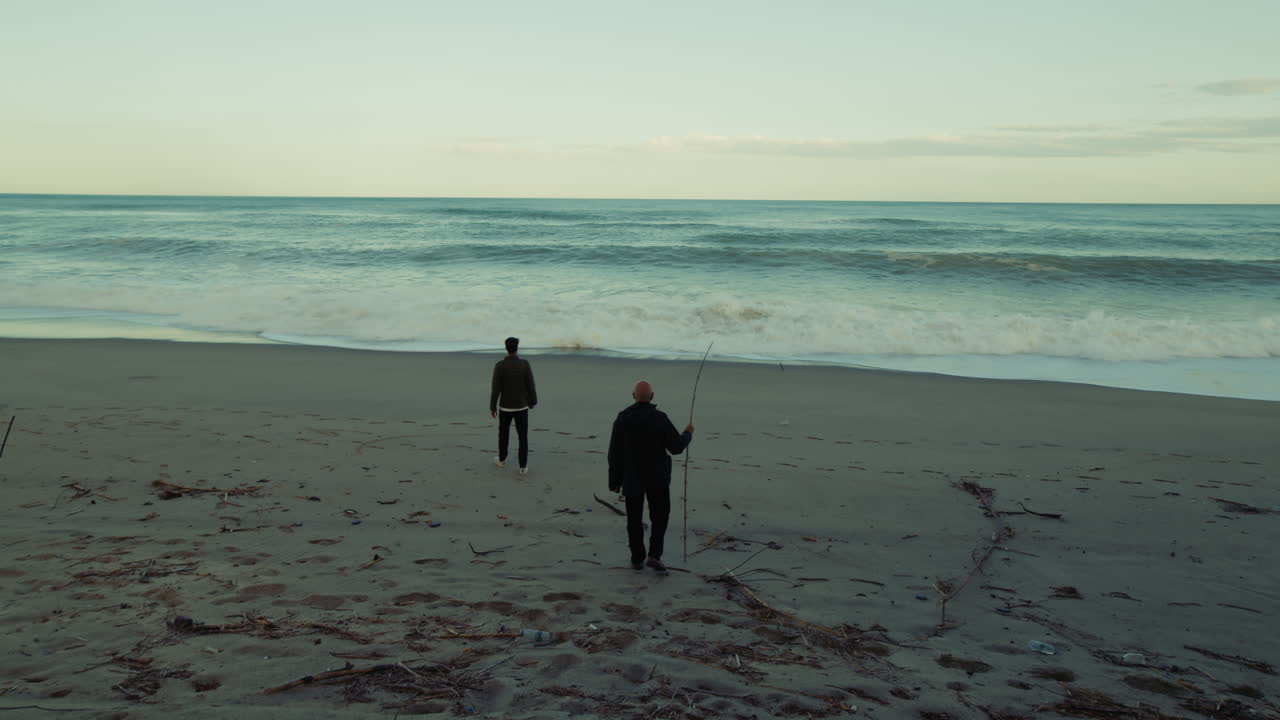 People Walk Down Towards Strong Ocean Waves From Beach
