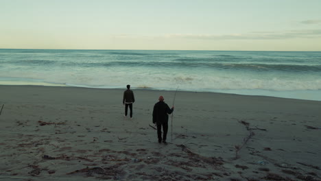 people walk down towards strong ocean waves from beach