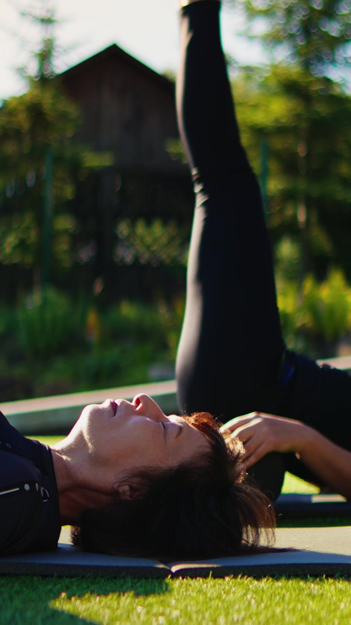 Mulher Madura Praticando Elevações de Pernas de Pilates em Tapete ao Ar Livre