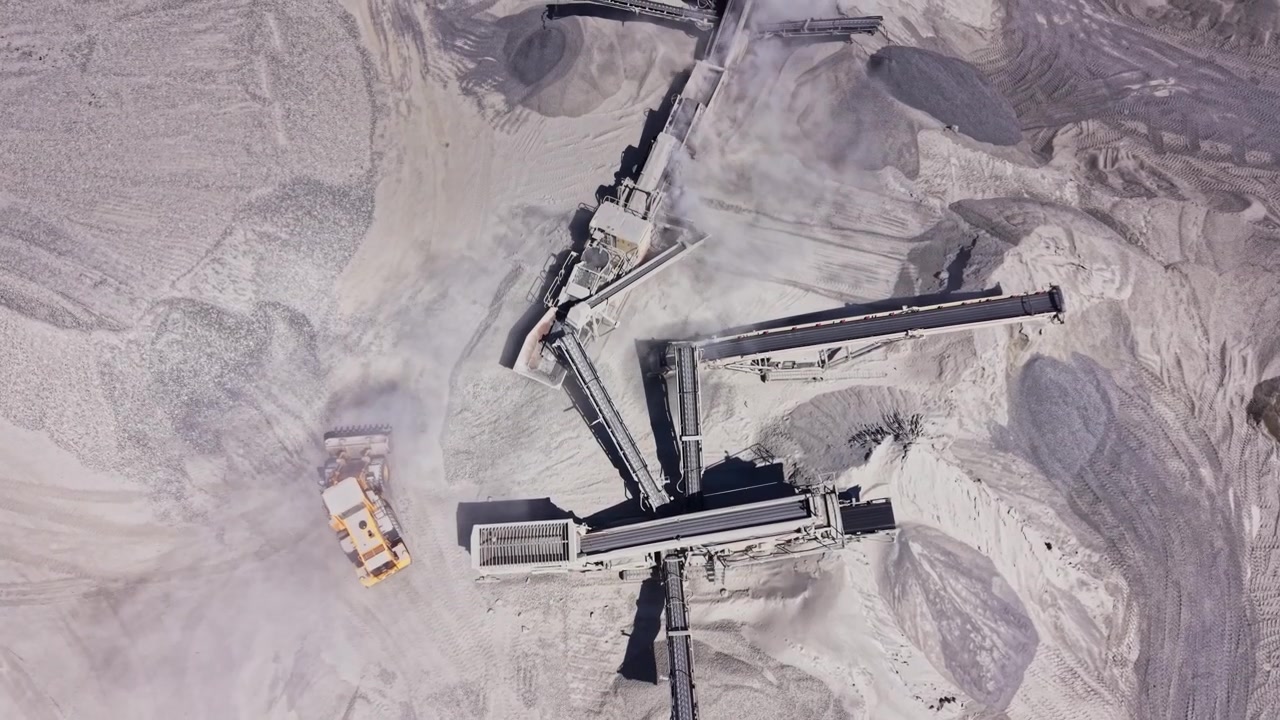 Heavy machinery operates in sand quarry during daytime