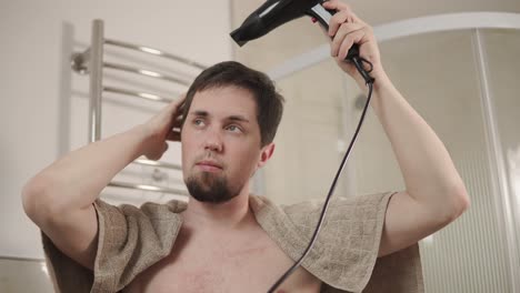hombre secándose el cabello en el baño