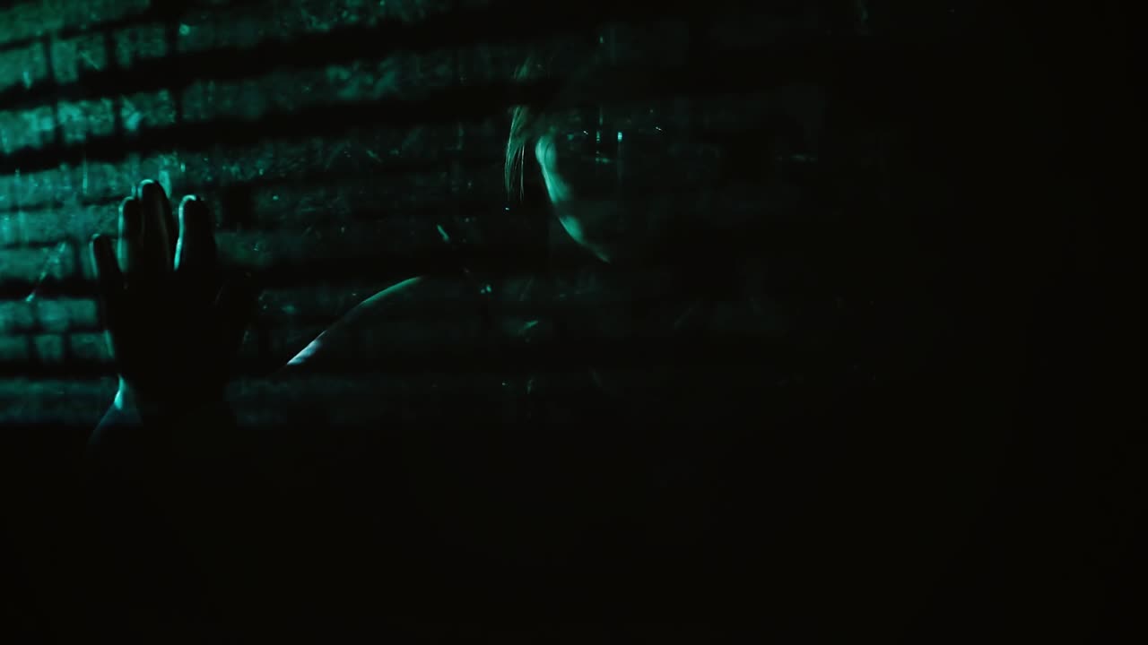 cu hacker chica está en la oscuridad detrás de la pantalla transparente y está estudiando el texto verde