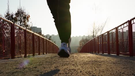 man running on a bridge at sunrise