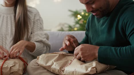 una pareja multiétnica abriendo regalos de navidad similares en casa.