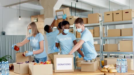 grupo multiétnico de voluntarios en cajas de embalaje de máscaras faciales con comida en almacén de caridad