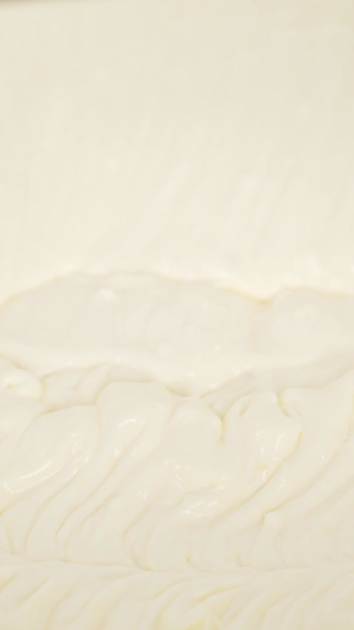 Close-up vertical shot of mixing cream dough, a crucial step in preparing tiramisu dessert.