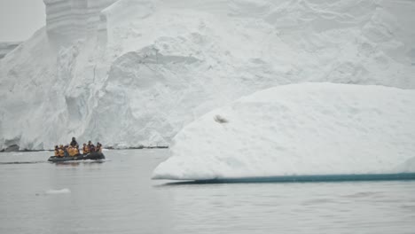 tourists on boat cruising along a long coastline in antarctica looking at ice bergs and glacier