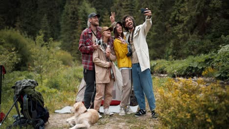 A-group-of-happy-tourists-in-special-hiking-clothes-take-a-selfie-against-the-backdrop-of-a-green-forest.-Active-lifestyle,-walking-and-hiking.-Selfie-as-a-memory-of-the-event