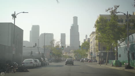 hazy city street scene with downtown skyline and visible tents