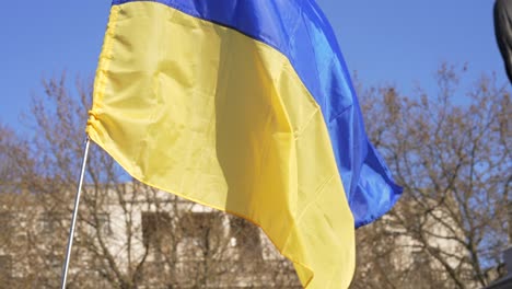 london stands with ukraine, ukrainian flag waving in trafalgar square in london during protest against war with russia, statue in the background