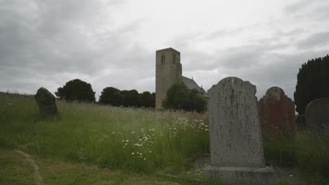 an old gravestone in an overgrown graveyard at a medieval christian church