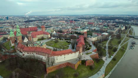 Vista-Panorámica-Del-Castillo-Real-De-Wawel-Junto-Al-Río-Vistula-En-La-Ciudad-De-Cracovia,-Polonia,-Con-El-Centro-De-La-Ciudad-Al-Fondo