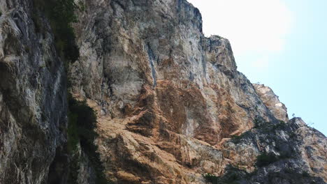 Upright-panning-shot-over-over-the-harsh-and-cliffy-mountain-line-on-a-sunny-day-at-Lago-di-Garda-in-Italy-near-the-Sentiero-del-Ponale