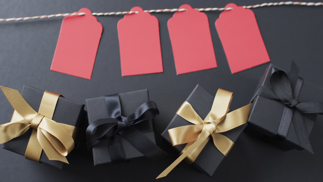 줄에 있는 선물 태그, 리본이 있는 선물 상자 및 검은색 배경에 있는 복사 공간의 비디오