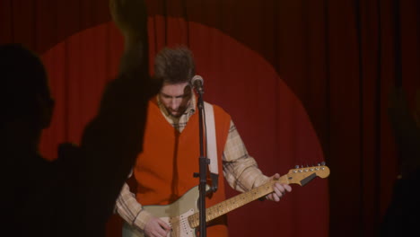 male musician playing guitar during live music perfomance