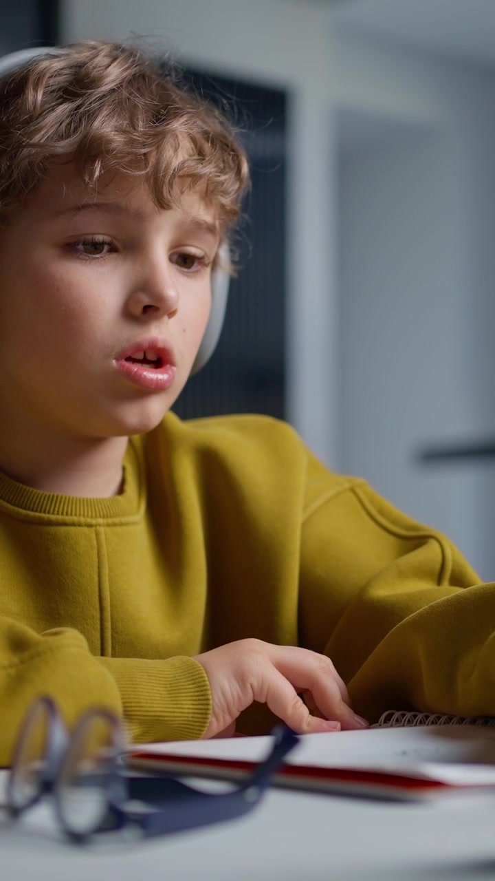Giovane ragazzo concentrato con le cuffie che scrive su un quaderno