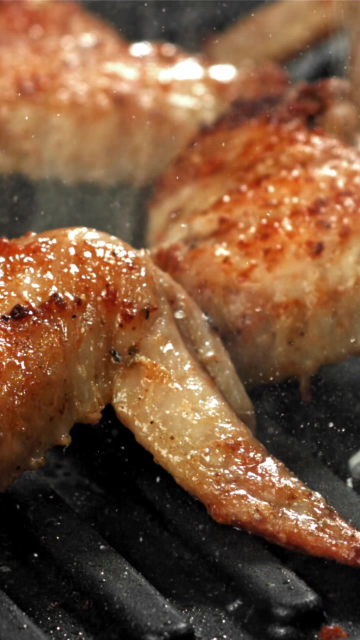 Primo piano di deliziose ali di pollo sfrigolanti su una piastra calda