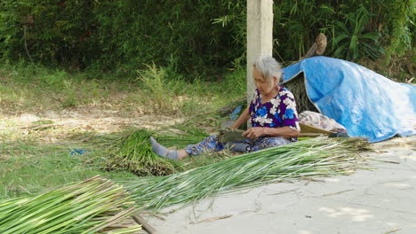 Ein-Erfahrener-Handwerker-Setzt-Seine-Werkzeuge-Geschickt-Ein,-Während-Er-Mit-Unerschütterlicher-Konzentration-Da-Sitzt-Und-In-Der-Provinz-Quang-Nam,-Vietnam,-Natürliche-Materialien-Mit-Präzision-Und-Sorgfalt-In-Kleinere-Stücke-Schneidet