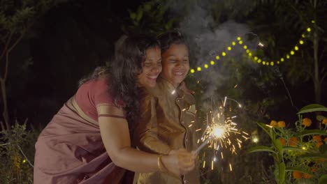 diwali celebrating a family family bursting firecrackers in diwali festival in india, mother and child enjoying with firecrackers
